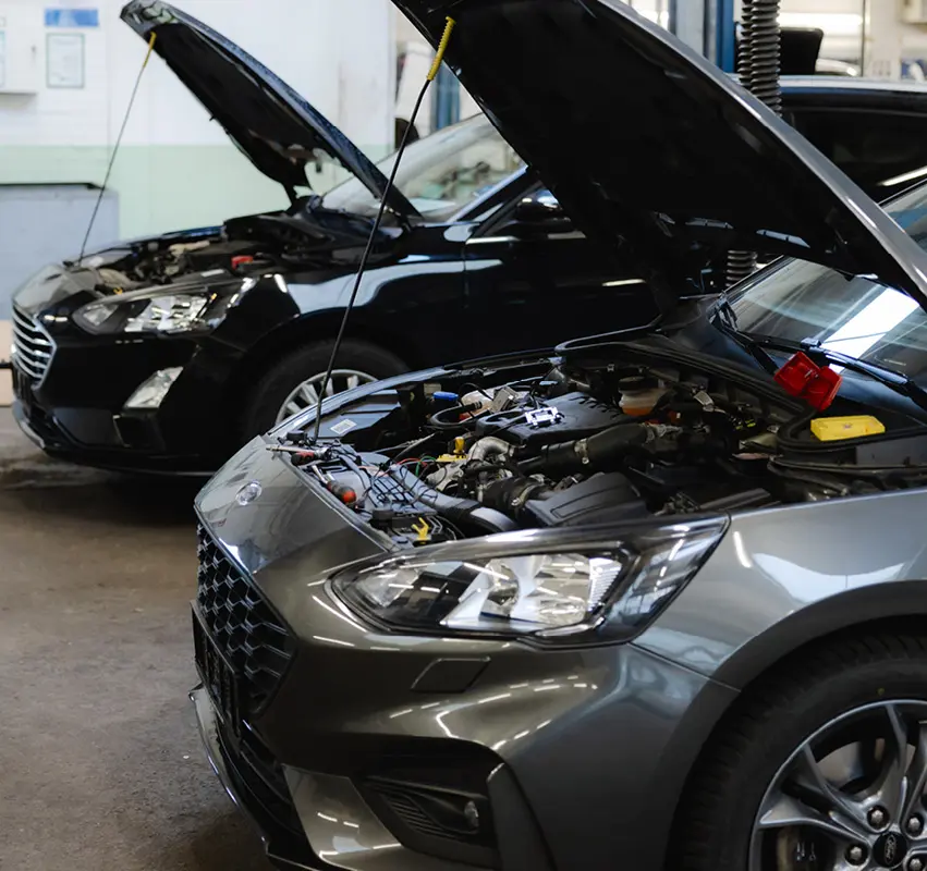 Autos stehen mit offenen Motorhauben in der Werkstatt